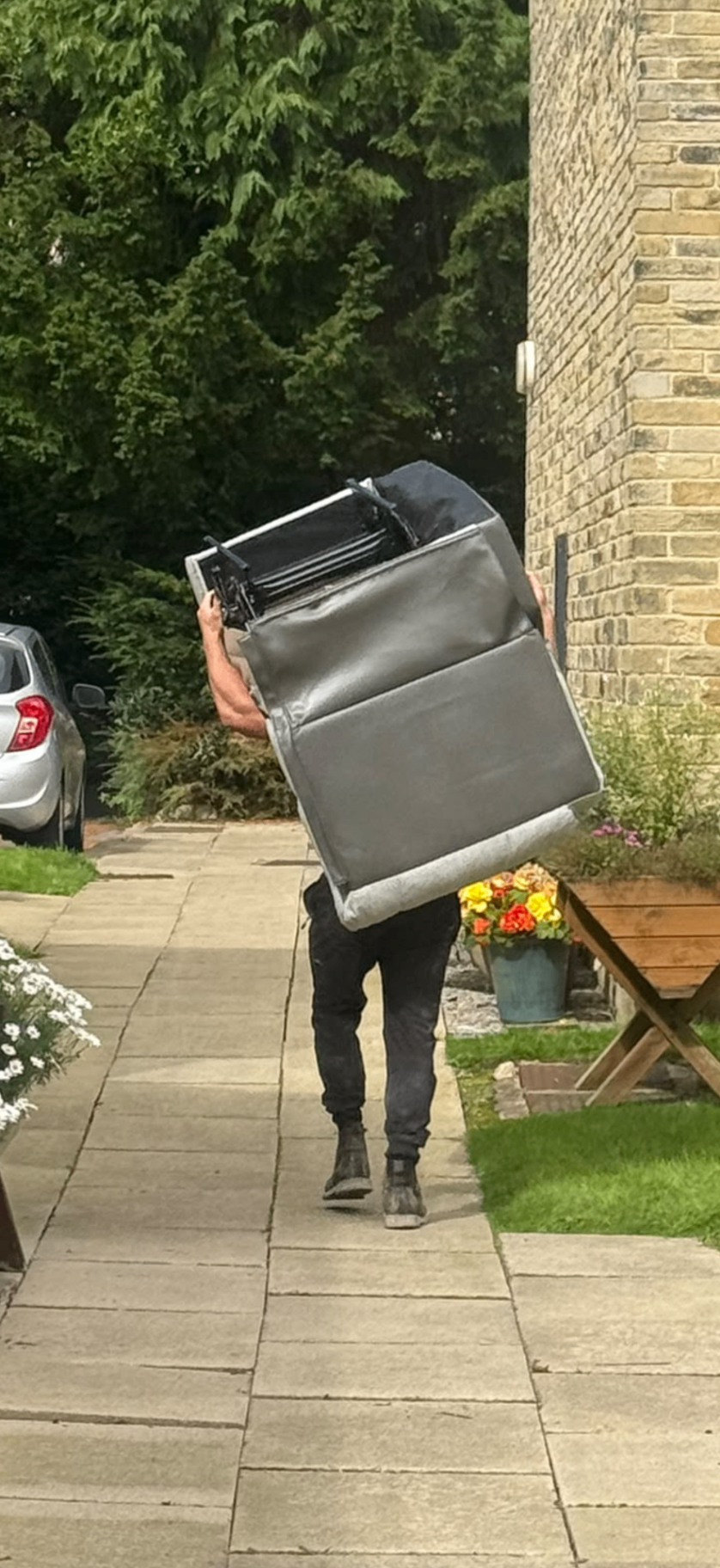 A member of the team carrying a sofa out of a property